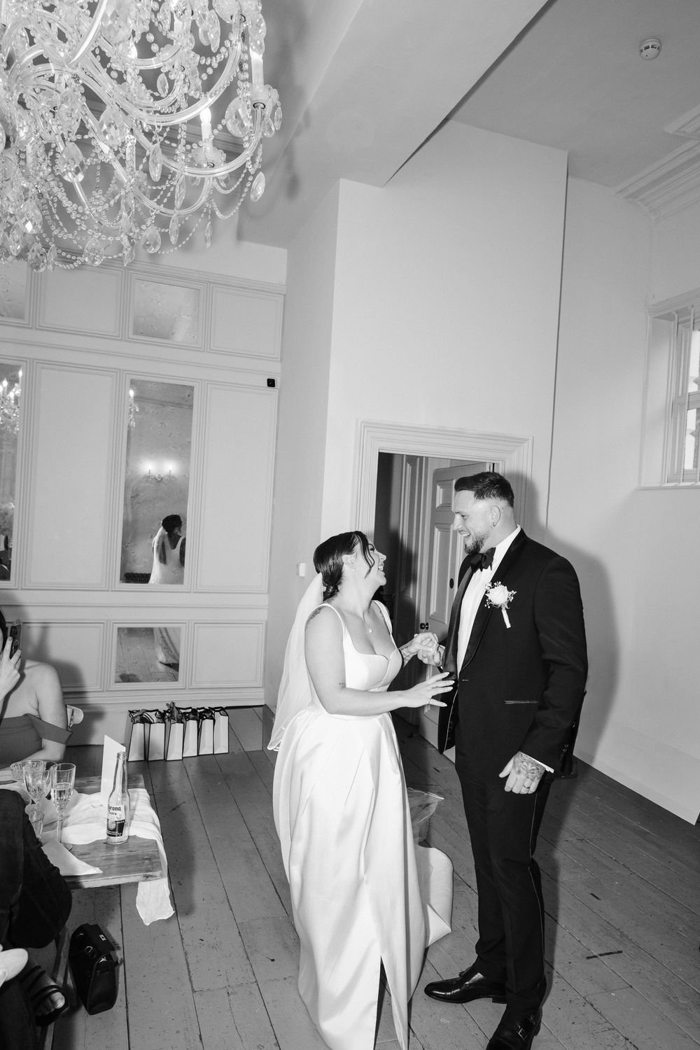 Black and white wedding photos capture playful dance moments between a couple in a bright elegant venue.
