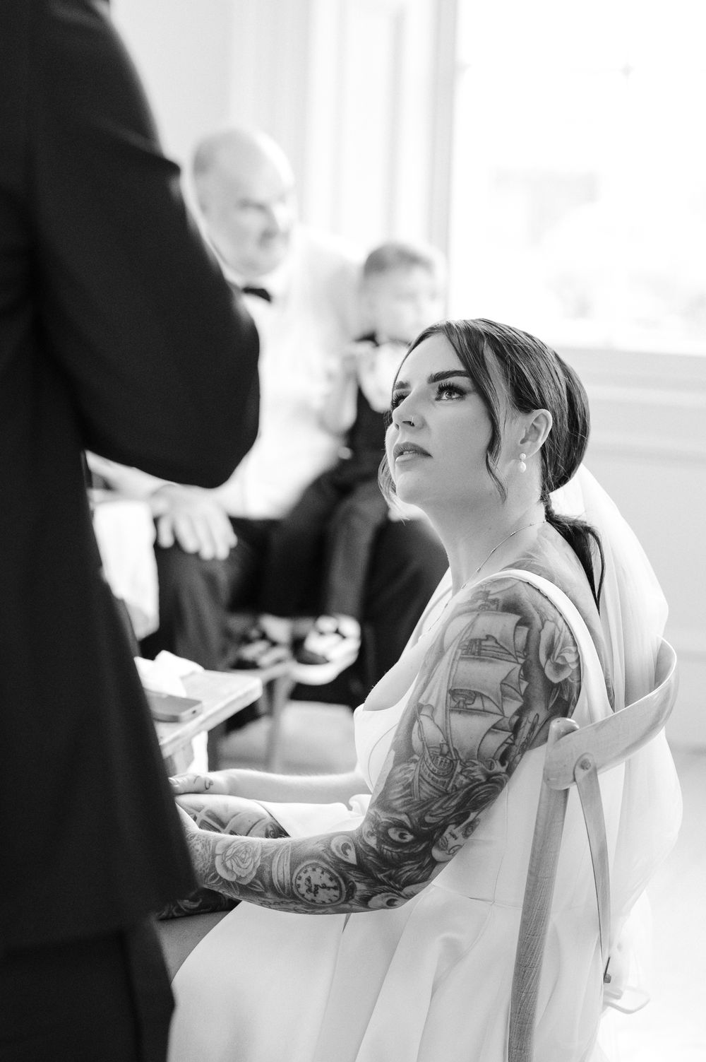 Black and white photo series showing person with floral arm tattoo leaning back in chair during styling session.