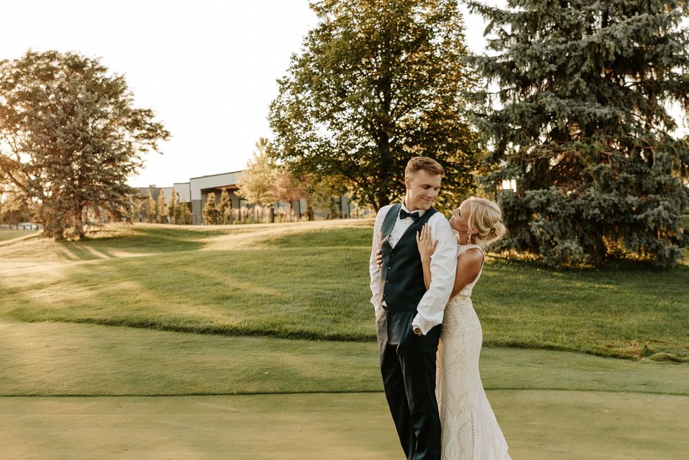 A couple shares a romantic moment on a scenic golf course during golden hour.