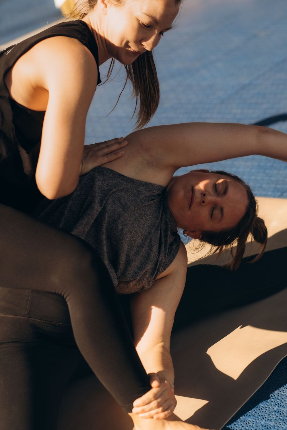 yoga teacher helping a woman to stay in yoga pose during brand yoga event while being captured by brand event photographer in Stockholm