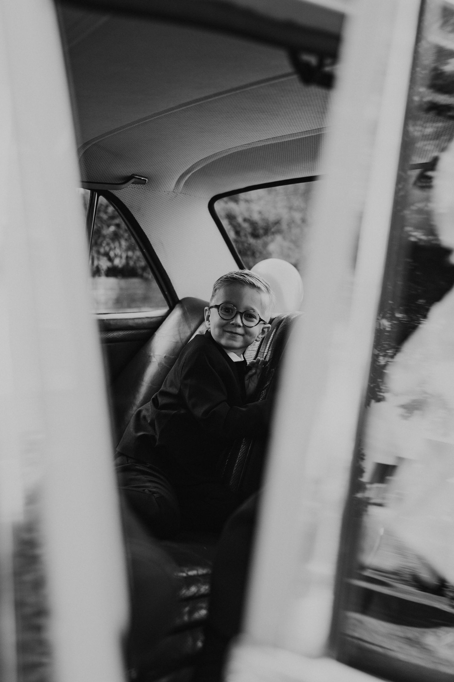 Black and white photograph of someone looking through a car window with vertical white lines in the foreground.