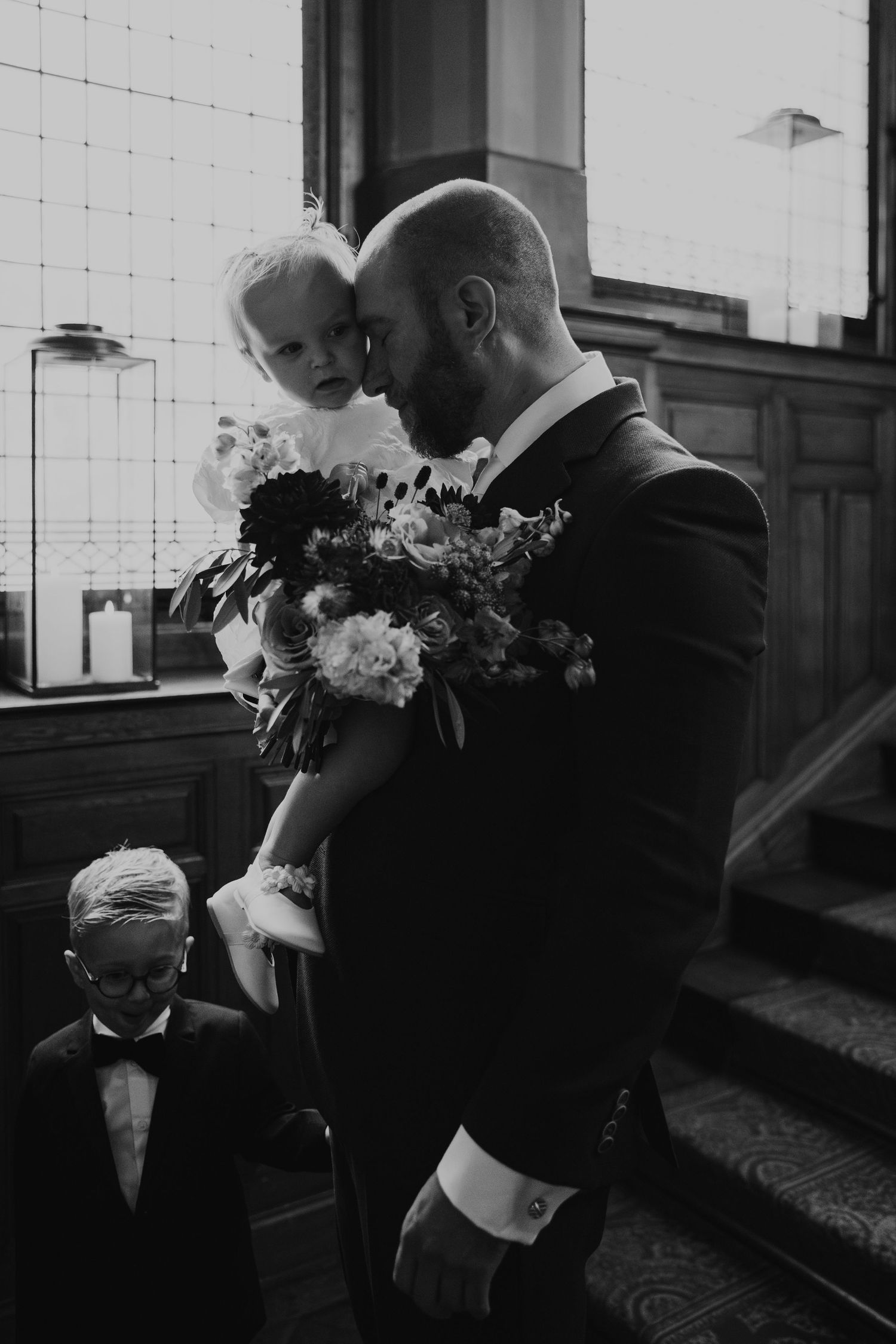 A tender black and white wedding moment on a staircase with a bouquet of flowers.