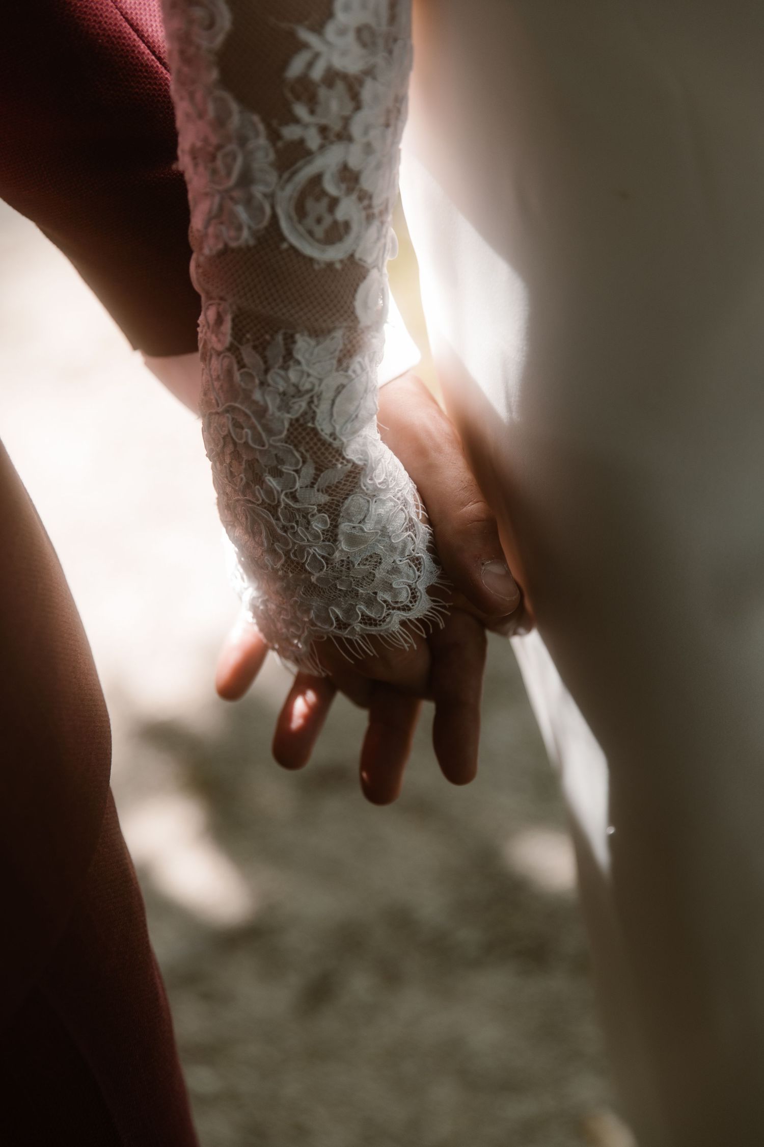 A close-up view of a delicate lace sleeve from a wedding dress with intricate floral patterns in natural lighting.