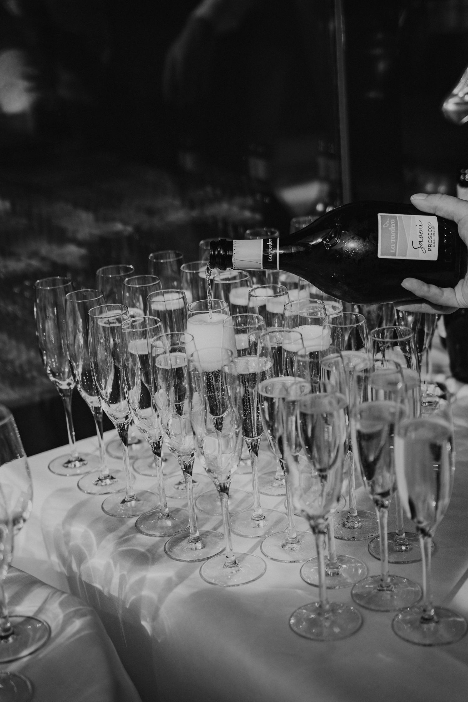 Elegant champagne flutes and wine glasses arranged on white tablecloth at formal event reception.