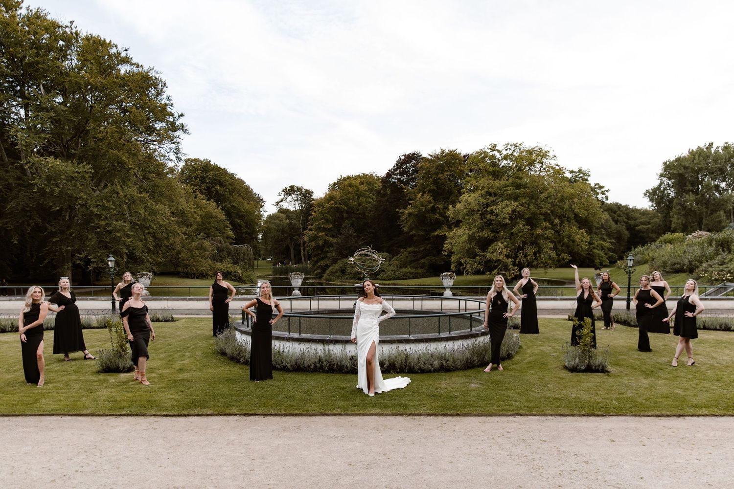 People gather in a park for an outdoor ceremony with trees in the background.