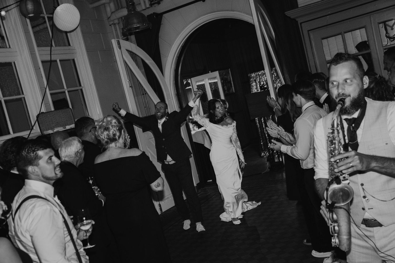 A black and white photo shows a crowded dance floor with people moving and socializing at a nightclub or party.