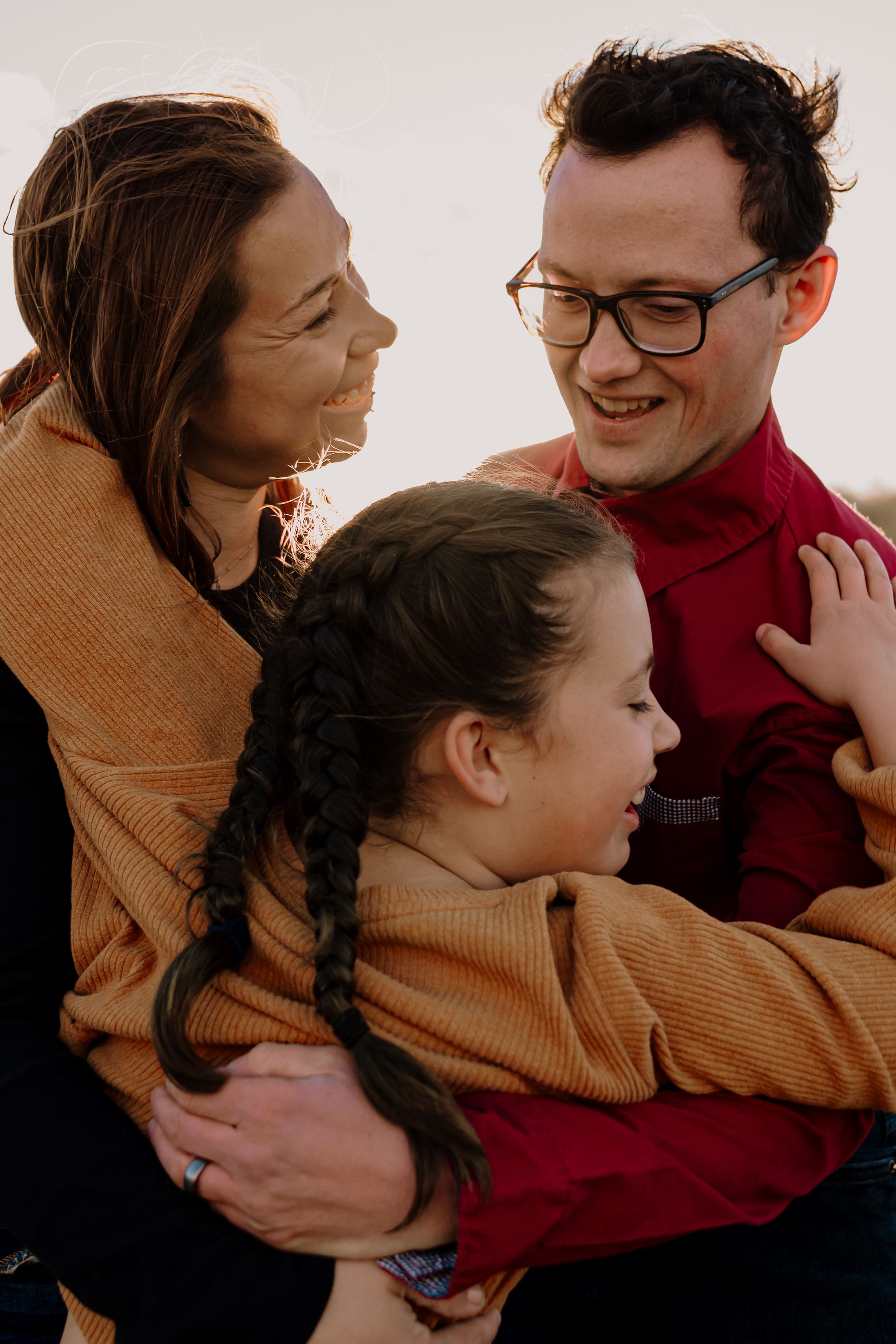 Couple in warm sweaters sharing intimate embraces and laughter during an outdoor photoshoot.