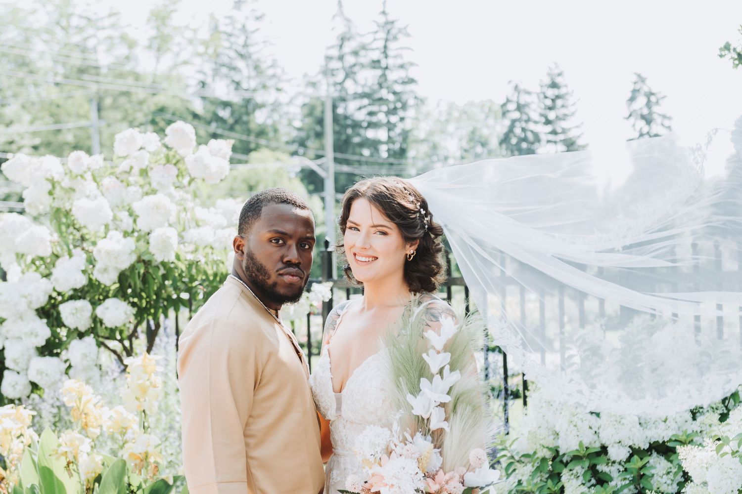 A romantic outdoor wedding photoshoot under a willow tree with soft natural lighting.