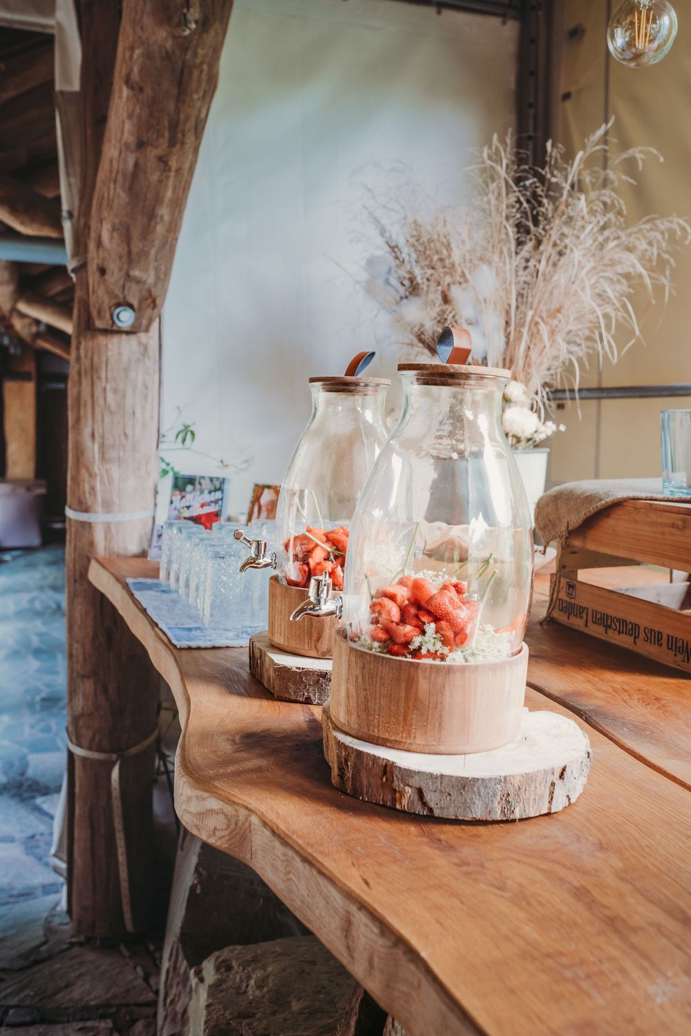 Rustic wooden table displays decorative glass cloches with dried flowers and natural elements arranged in a row.