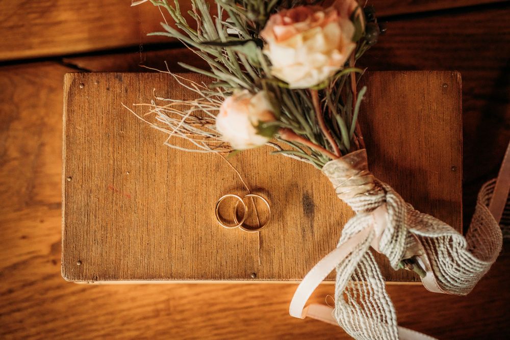 Rustic wedding decor features delicate floral arrangements with white roses and dried grasses against wooden panels.