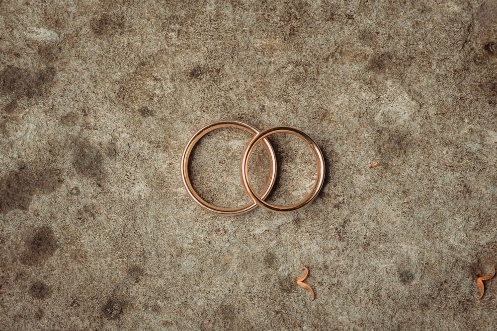 Copper wire rings and jewelry pieces laid out in sequence on a textured gray concrete surface.