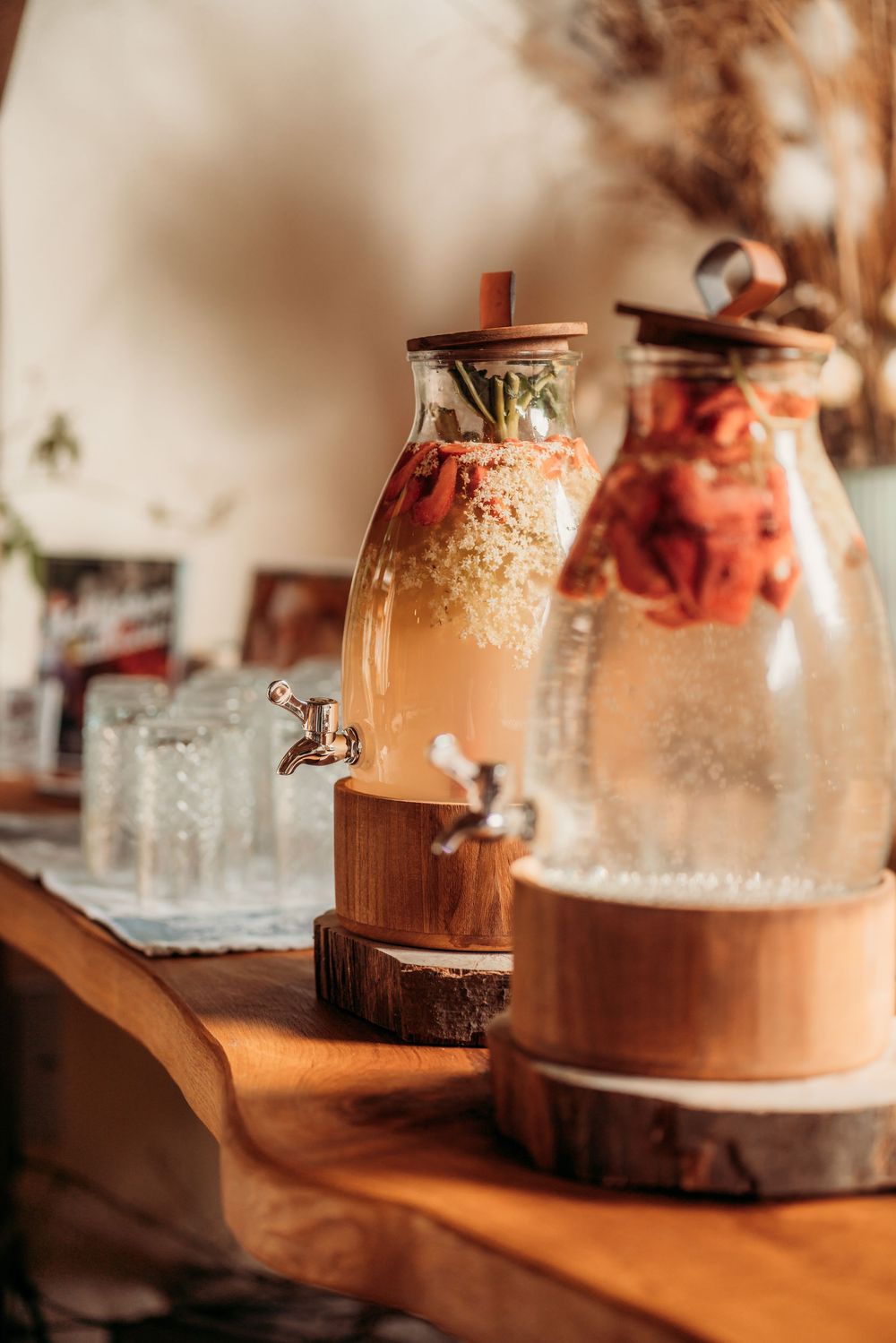 Glass jars filled with pink and brown desserts sit on a rustic wooden surface in warm lighting.
