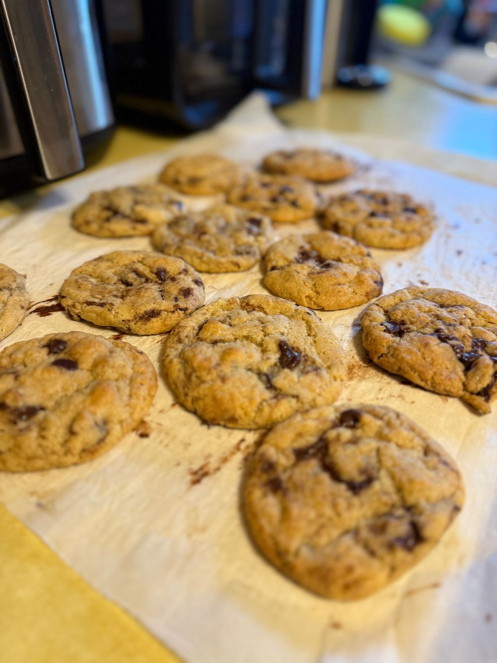 Homemade chocolate chip cookies arranged in rows on parchment paper.