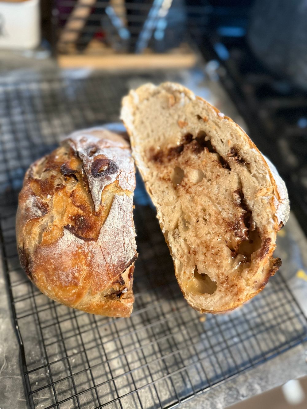 Close-up shots of freshly baked sourdough bread with a cracked crust cooling on a wire rack.