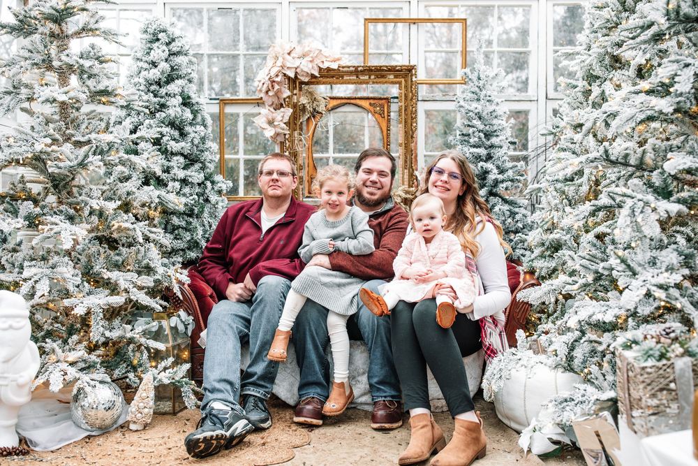 A series of winter family photos with snow-covered evergreen trees and festive holiday decorations in the background.