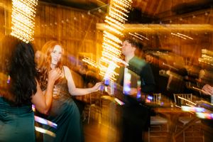 Wedding guests dancing with bokeh lights in warm golden barn reception venue atmosphere.