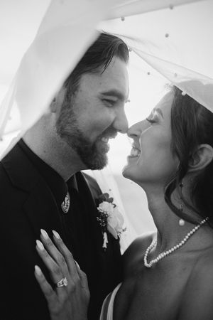 Black and white romantic wedding portrait of bride and groom sharing an intimate moment under her veil.