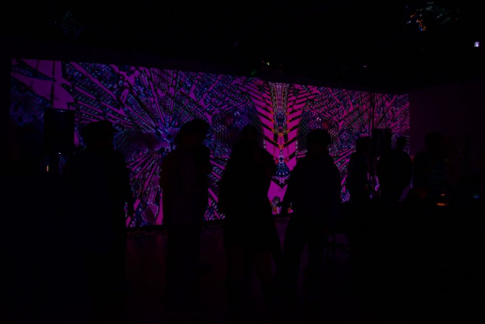 NikitaVisiion, founder of MHYSA Consultancy projecting her immersive visual art projected on art gallery walls with a crowd watching