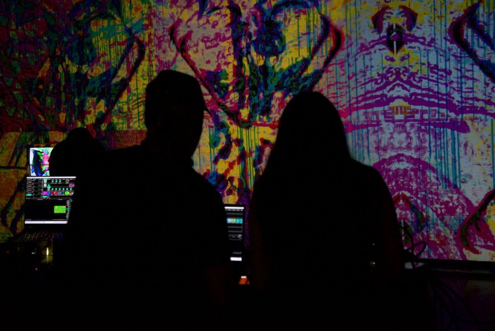 NikitaVisiion, founder of MHYSA Consultancy projecting her immersive visual art projected on art gallery walls with a crowd watching