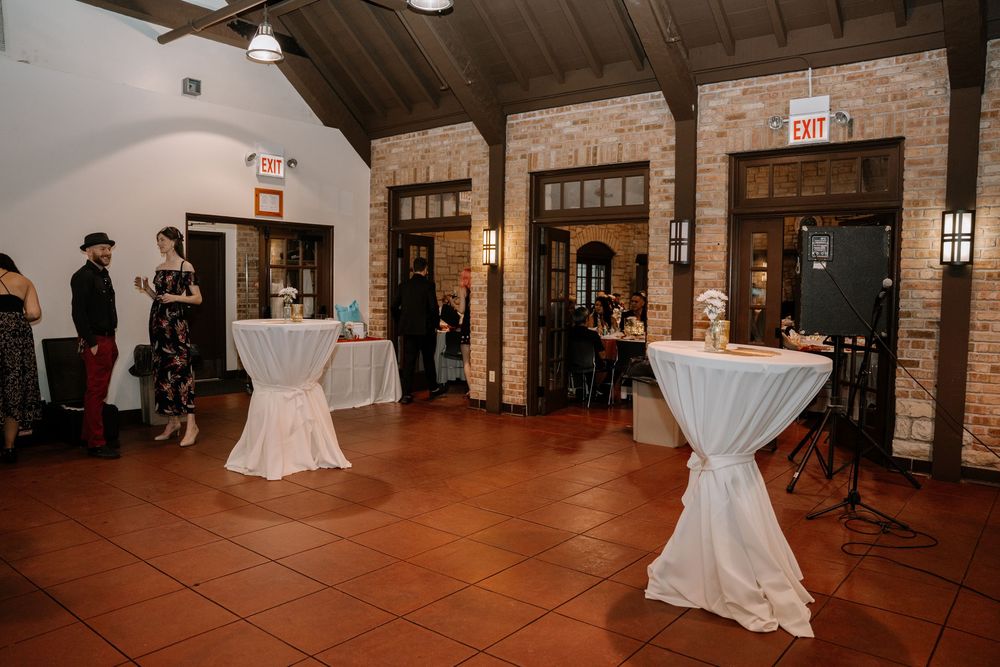 Wedding reception venue with exposed wooden beams and stone walls features elegant table settings and white decor.