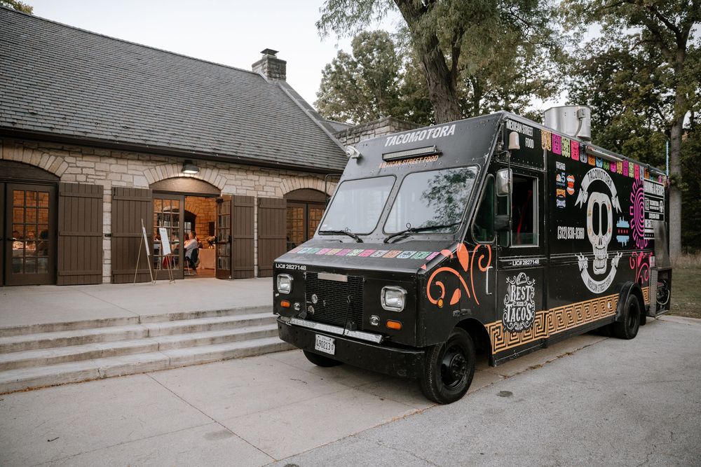 A series of black food trucks and mobile vendors parked in a row at an outdoor event.