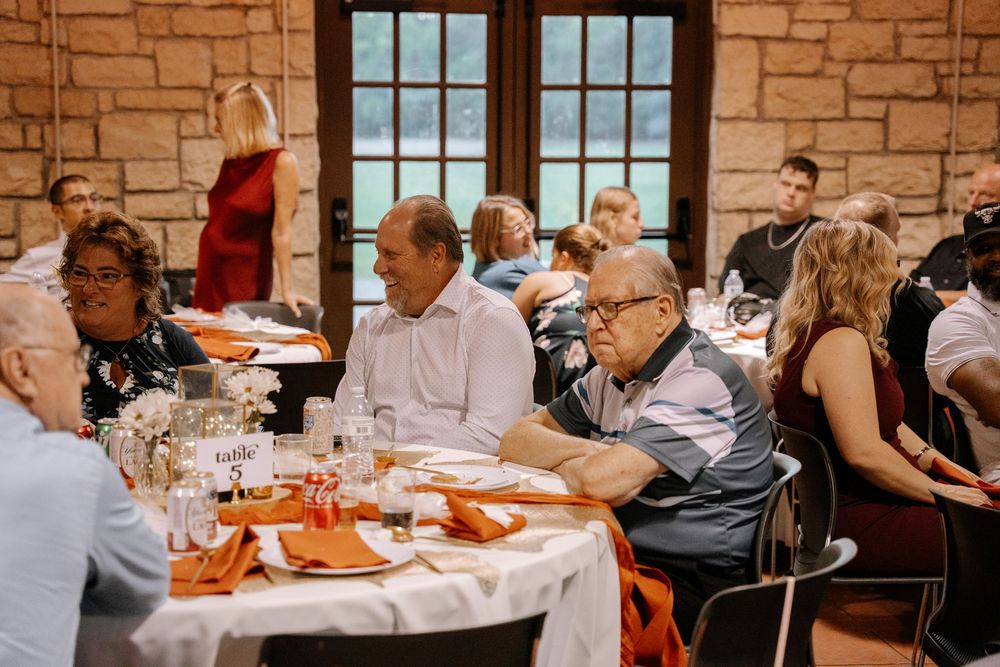 Business professionals gathered around tables in a stone-walled conference room during a meeting or workshop session.