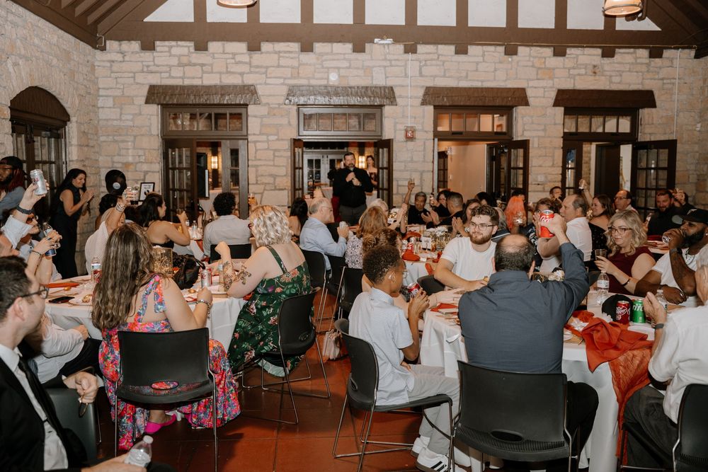 Wedding guests enjoying a celebration in a rustic indoor venue with stone walls and warm lighting.