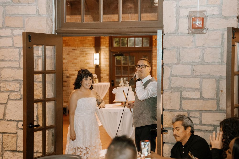 Wedding guests enjoying a candlelit dinner reception in an elegant stone-walled venue with warm lighting.