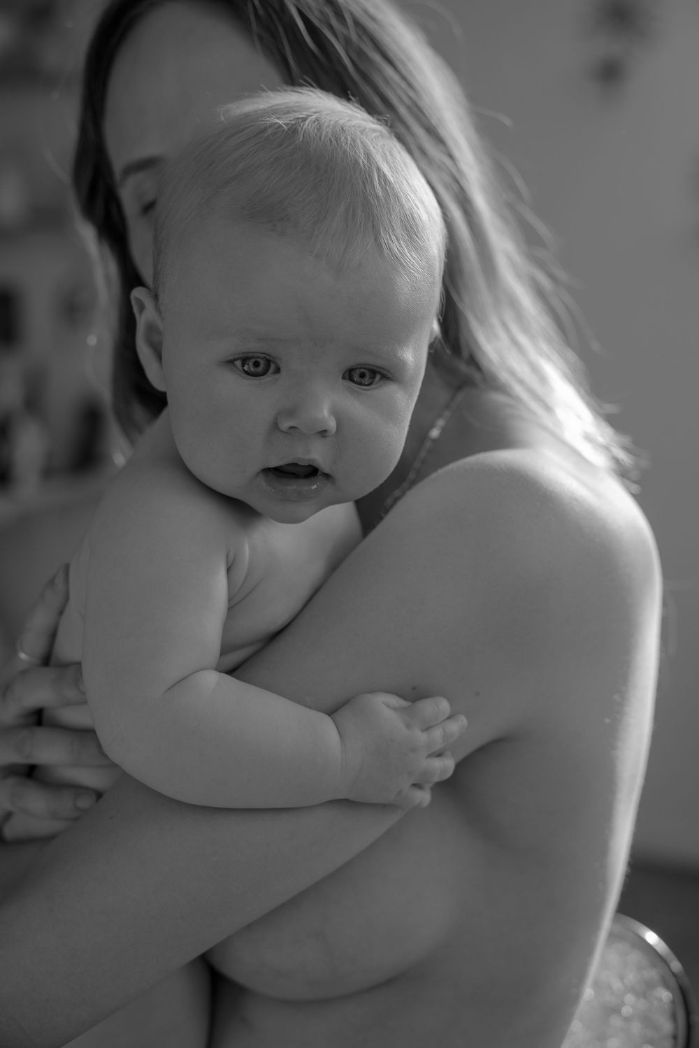 Black and white image capturing intimate bonding moment between parent and infant.