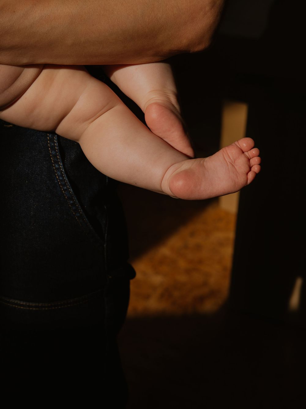 Close-up view of tiny baby toes and feet against a dark background.