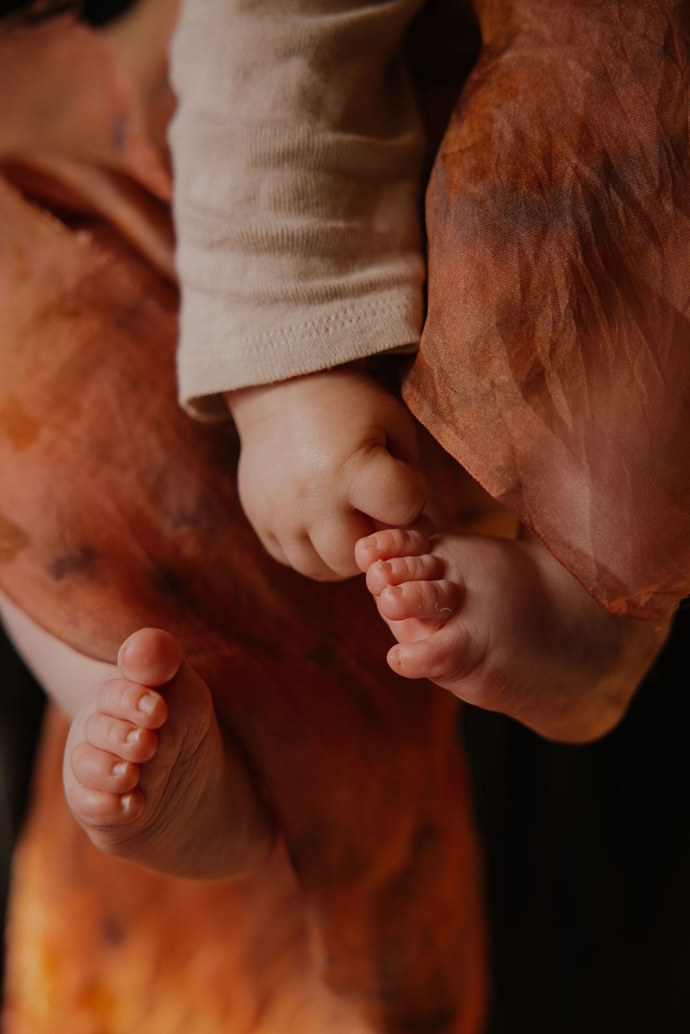 A series of five connected images showing tiny baby toes in warm lighting against a brown background.