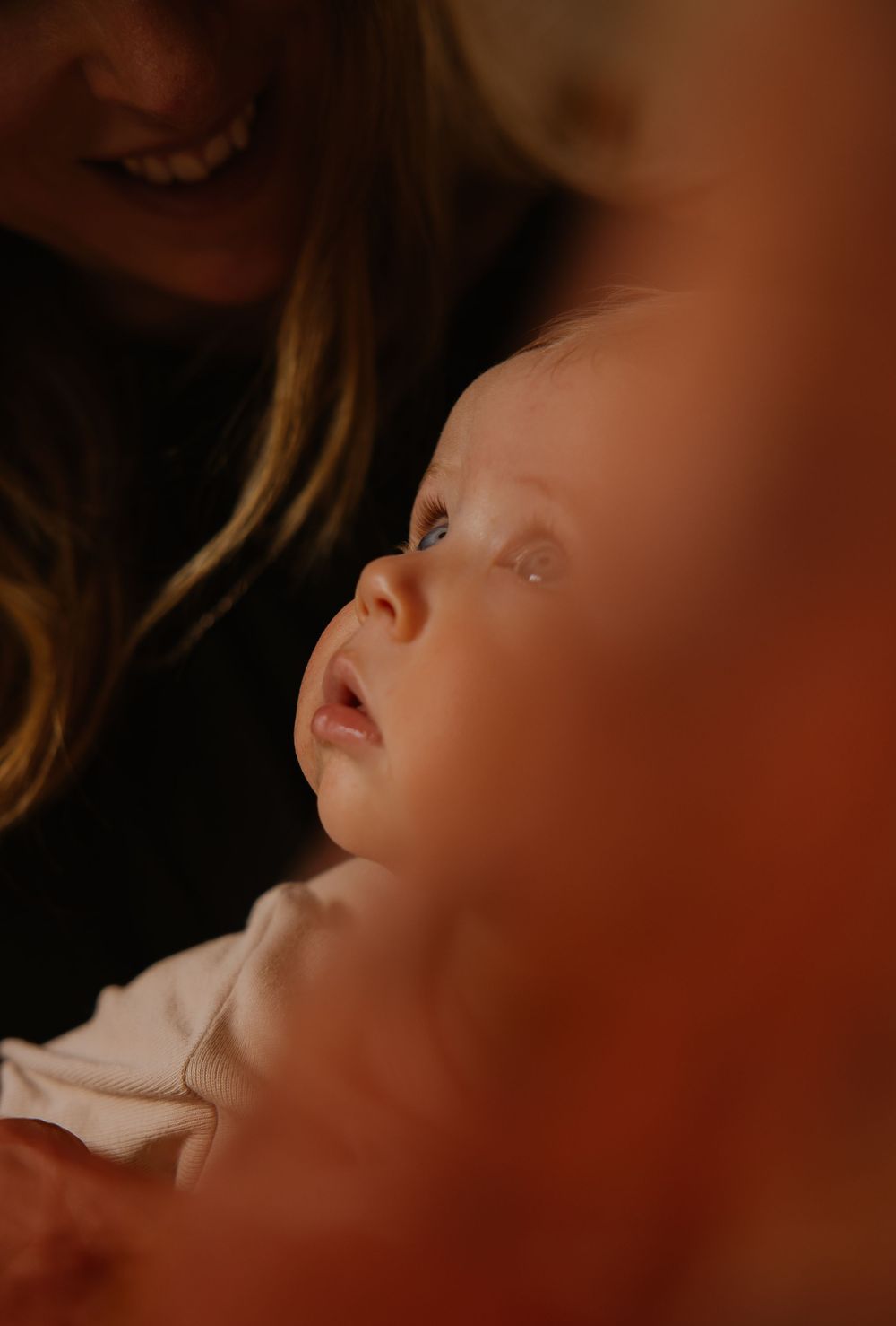 Close up portrait of baby looking up with dreamy expression in warm atmospheric lighting.