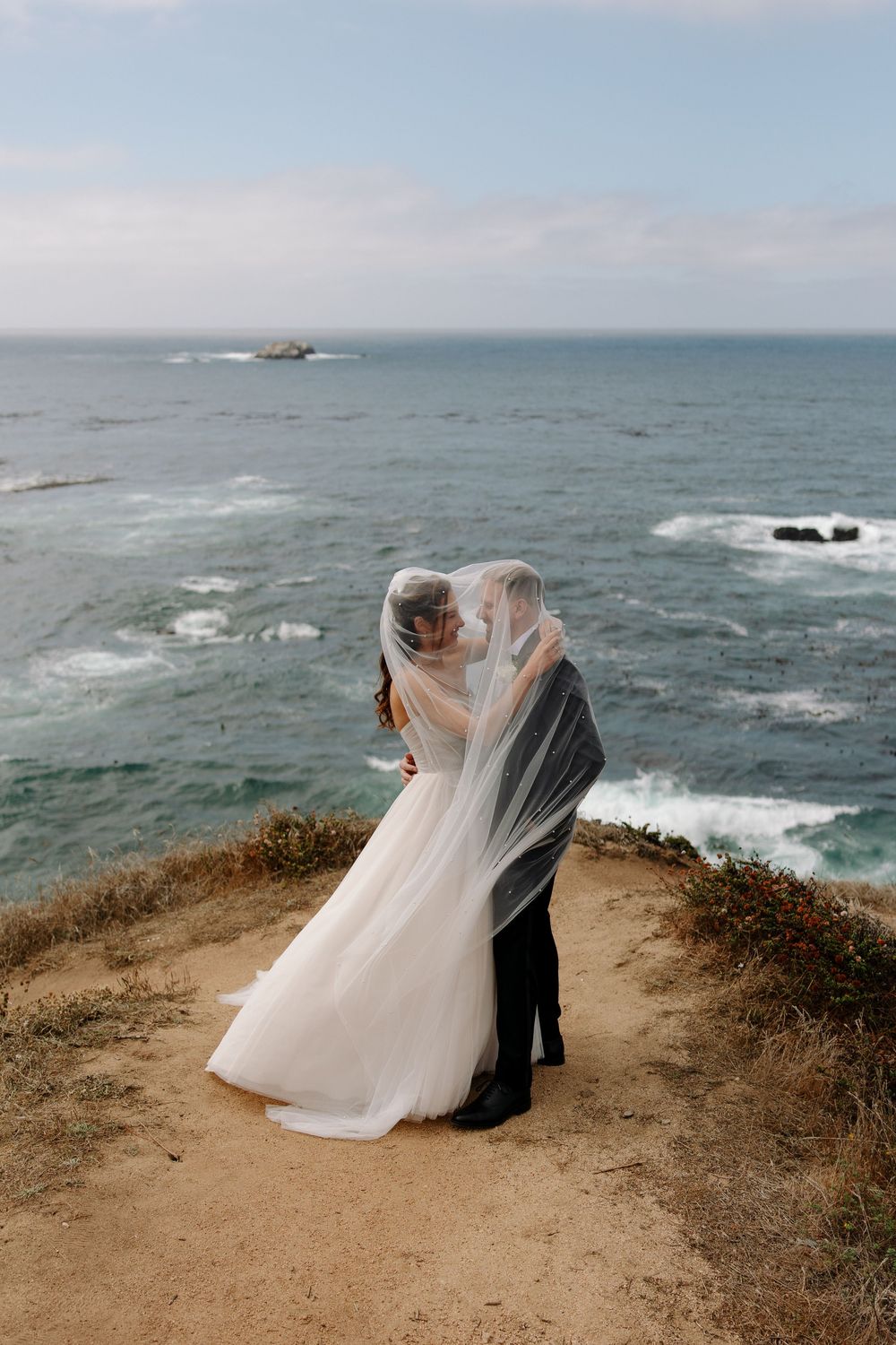 Dramatic wedding photos on coastal cliffs with flowing white dress catching the ocean breeze.