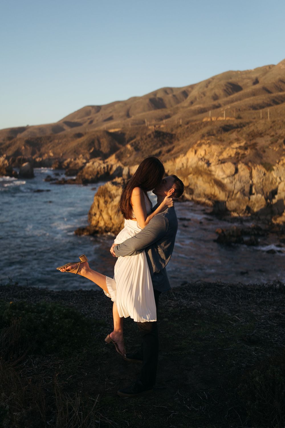 Romantic sunset photoshoot on rugged coastal cliffs overlooking the ocean.