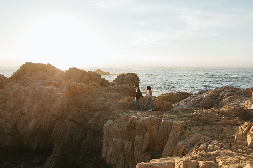 Dramatic coastal landscape at sunset with rocky cliffs and ocean waves.