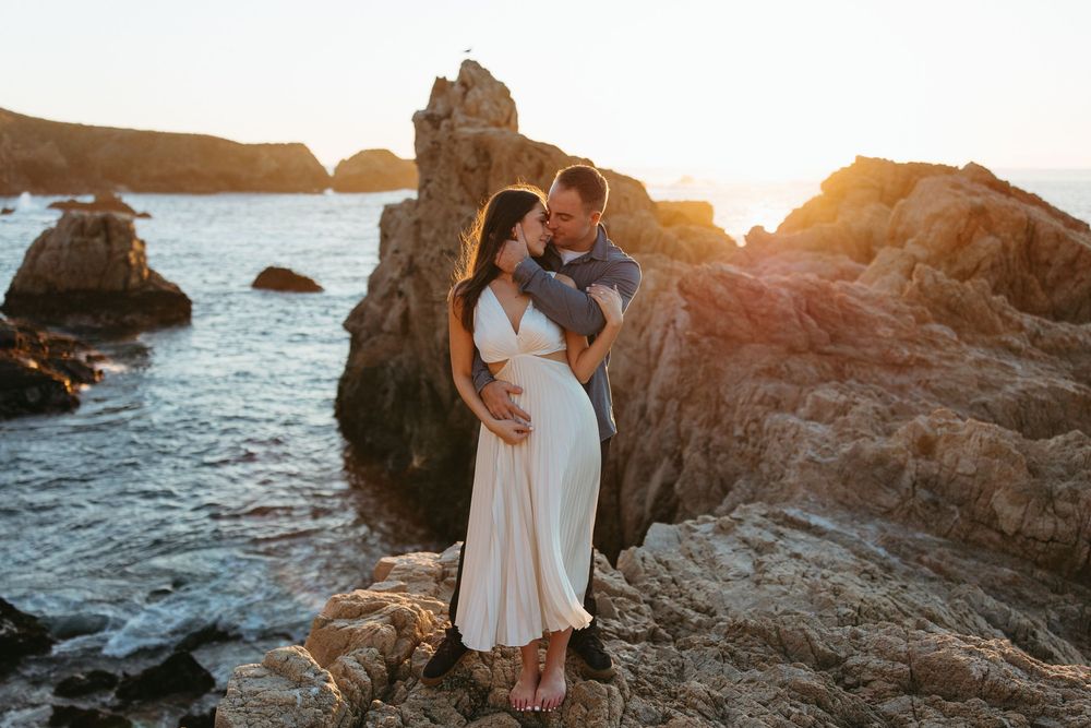 Romantic sunset moment on rocky coastal cliffs with ocean waves crashing below.