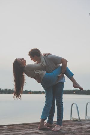 Playful dance poses on a wooden dock overlooking a serene lake.