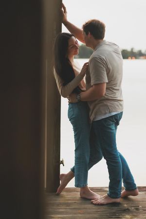 A tender moment shared on a wooden dock overlooking a serene waterfront at dusk.