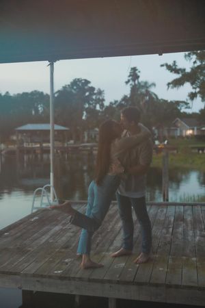 Silhouettes dancing on a wooden dock with water views at twilight.