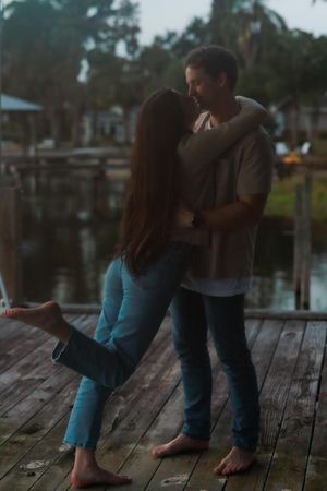 Couple sitting together on a wooden dock at sunset sharing an intimate moment by the water.