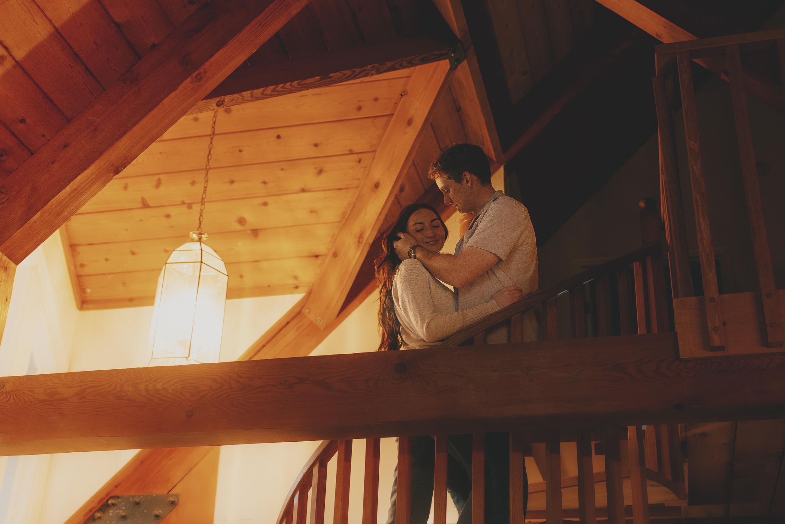 Couple dancing in a rustic wooden cabin with warm lighting and exposed beams.