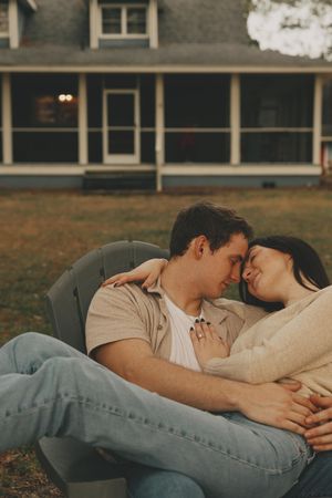 A couple lying together on grass in casual clothing during a tender outdoor moment.