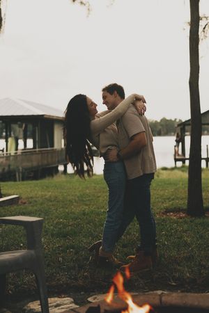 A couple shares a romantic dance outdoors with a fire pit glowing in the foreground.
