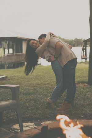 Two people dancing near a fire pit in a backyard setting.