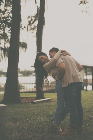 Couple dancing together on a grassy lawn with trees in the background.