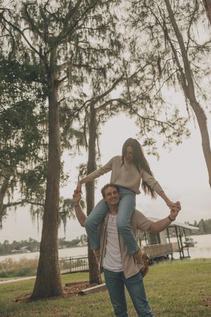 A playful moment captured outdoors under moss-draped trees near a waterfront.