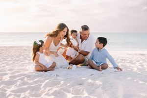 Family playing and bonding together on a pristine white sandy beach at sunset.