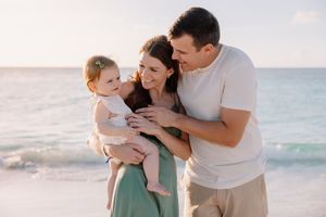 Family sharing an intimate moment together on a beach with ocean waves in background.