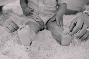 Close-up black and white detail shots of hands touching sand on the beach.