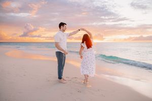 Group enjoying a beautiful sunset moment on a tropical beach with orange sky.